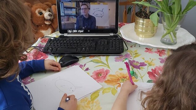 Deux petites filles regardent une vidéo, tout en dessinant.