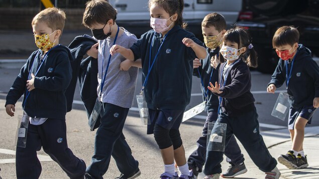 Des enfants qui portent le masque traversent la rue à Vancouver.
