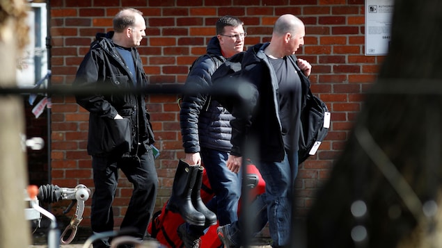 Trois hommes transportent des sacs près d'un immeuble en brique. Trois hommes transportent des sacs près d'un immeuble en brique.