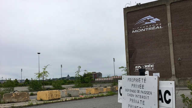 L'entrée d'un des bâtiments de l'hippodrome de Montréal, avec une pancarte indiquant «propriété privée», «défense de passer» et « chien interdit» et des blocs de béton.