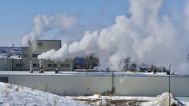 Une usine avec beaucoup de fumé qui s'échappe des tuyaux.