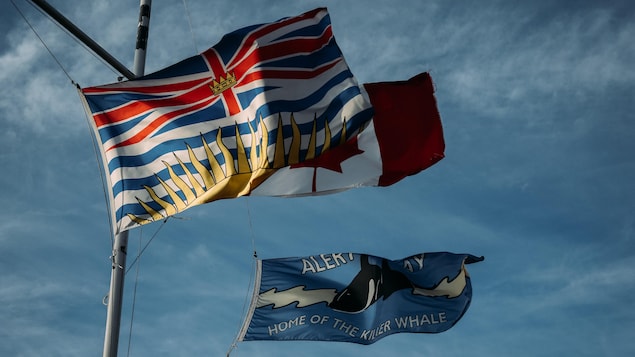 Des drapeaux : celui de la Colombie-Britannique, celui du Canada et un à l’effigie des épaulards, à Alert Bay, en Colombie-Britannique, au mois d'octobre 2022.