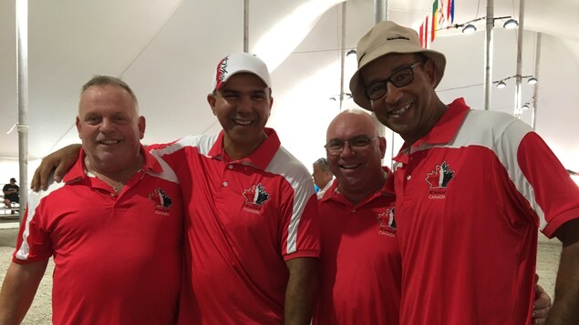 Quatre hommes avec des chandails à effigie du Canada sourient à la caméra. Quatre hommes avec des chandails à effigie du Canada sourient à la caméra.