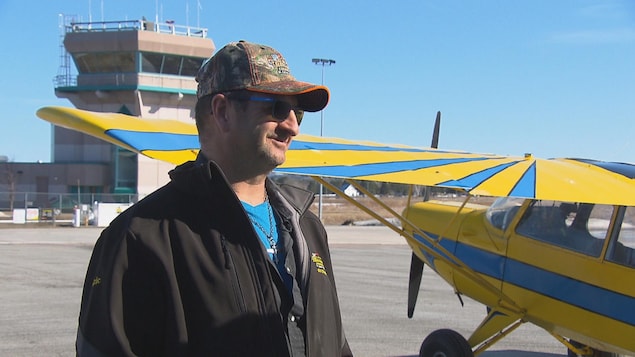 Un homme accorde une entrevue devant son avion sur le tarmac de l'aéroport de Roberval.