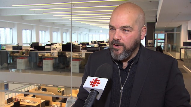Éric Trottier se trouve dans les bureaux de La Presse et parle dans un micro de Radio-Canada. Éric Trottier se trouve dans les bureaux de La Presse et parle dans un micro de Radio-Canada.