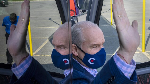 Erin O'Toole lève la main en sortant de son autobus de campagne.