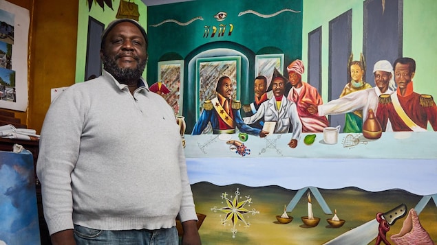 On voit M. Sévère, de face, debout devant la fresque représentant Toussaint Louverture et d'autres personnages historiques haïtiens réunis autour d'une table. On voit M. Sévère, de face, debout devant la fresque représentant Toussaint Louverture et d'autres personnages historiques haïtiens réunis autour d'une table.