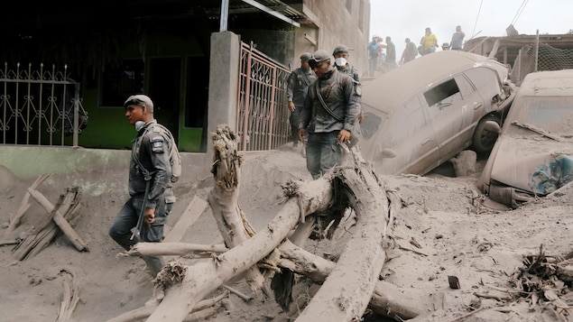 Des policiers traversent les décombres et les débris dans une rue de la ville d'Escuintla, au Guatemala, après l'éruption du volcan de Fuego. Des policiers traversent les décombres et les débris dans une rue de la ville d'Escuintla, au Guatemala, après l'éruption du volcan de Fuego.