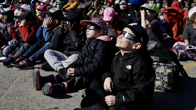 Des enfants regardent l'éclipse munis de lunettes de protection.