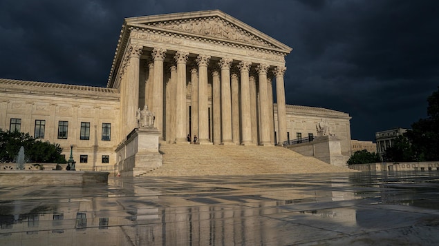 La Cour suprême des États-Unis vue en contre-plongée, sous un ciel nuageux.