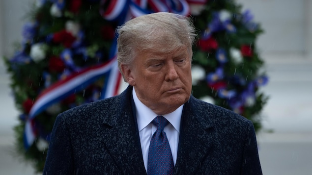 Le président sortant Donald Trump est debout devant une couronne mortuaire.