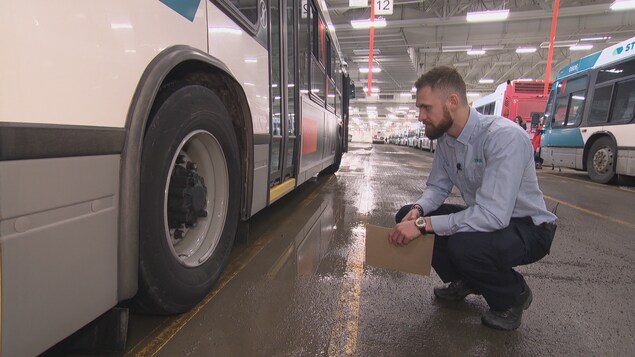 Un homme accroupi près de la roue d'un autobus prend des notes. Un homme accroupi près de la roue d'un autobus prend des notes.