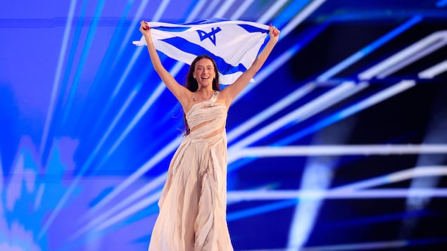 Eden Golan sur scène, brandissant un drapeau israélien.