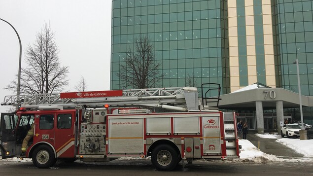 Un camion de pompier est garé devant l'édifice vitré. Un camion de pompier est garé devant l'édifice vitré.