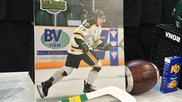Une photo d'un hockeyeur sur lequel est inscrit: Broncos de Humboldt. et et un baton de hockey. Une photo d'un hockeyeur sur lequel est inscrit: Broncos de Humboldt. et et un baton de hockey.