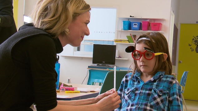 Une jeune fille reçoit un examen de la vue dans une classe lors d'une activité de sensibilisation.