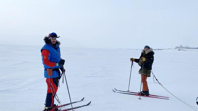 Deux des aventuriers, skis aux pieds, partent du village.
