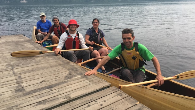 Cinq personnes à bord d'un canot arrivant à quai.