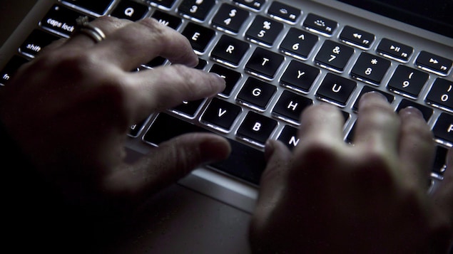 Des mains devant un clavier d'ordinateur.
