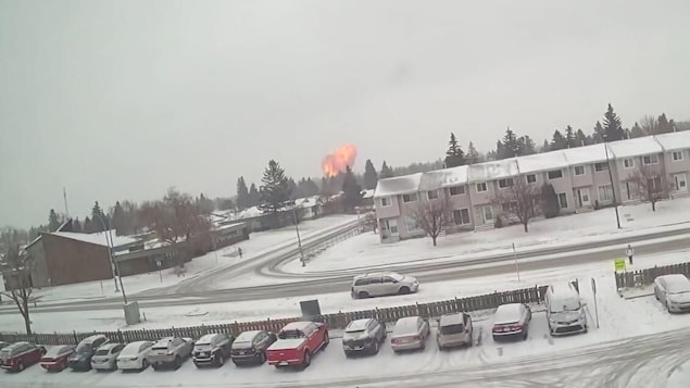 Une vidéo de surveillance montre une explosion projetant des débris en arrière-plan d'un quartier résidentiel. 