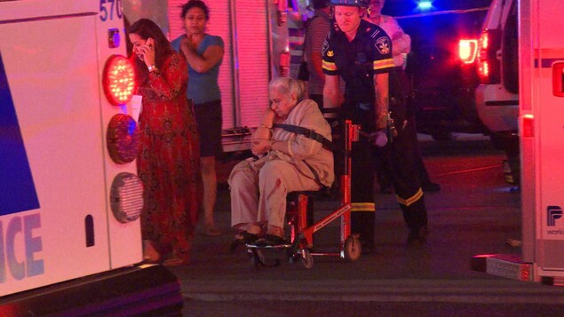 Photo d'une aînée en fauteuil roulant poussée par un ambulancier. Photo d'une aînée en fauteuil roulant poussée par un ambulancier.