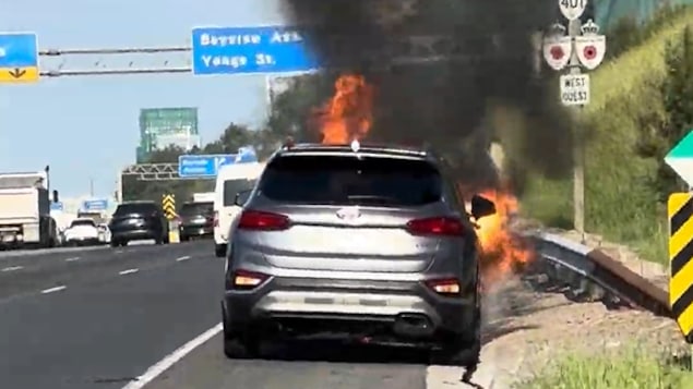 Une voiture en flamme sur le bord de l'autoroute.