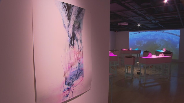 Un tableau et d'autres oeuvres au lieu dans une pièce sombre.
