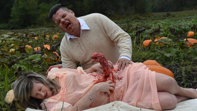 Nicole Cameron prétend donner naissance à un extraterrestre qui émerge de son ventre et Todd Cameron a le visage aspergé de sang. Nicole Cameron prétend donner naissance à un extraterrestre qui émerge de son ventre et Todd Cameron a le visage aspergé de sang.