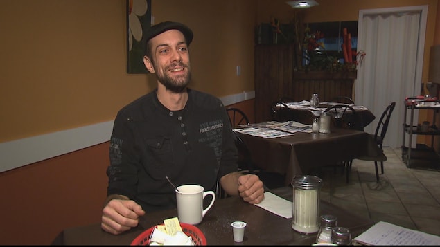 Un homme assis à une table dans un café. Il sourit. Un homme assis à une table dans un café. Il sourit.