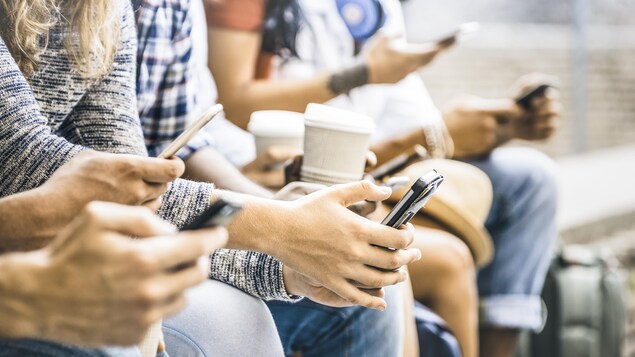 Plusieurs personnes assises manient un téléphone intelligent.