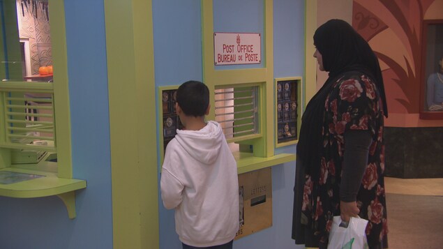 Une femme et son fils expérimentent un bureau de poste dans un musée pour enfants. Une femme et son fils expérimentent un bureau de poste dans un musée pour enfants.