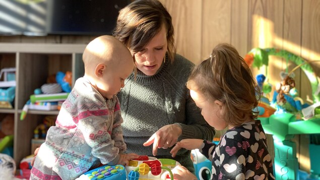 Jessica qui joue avec ses deux enfants en bas âge dans une maison.