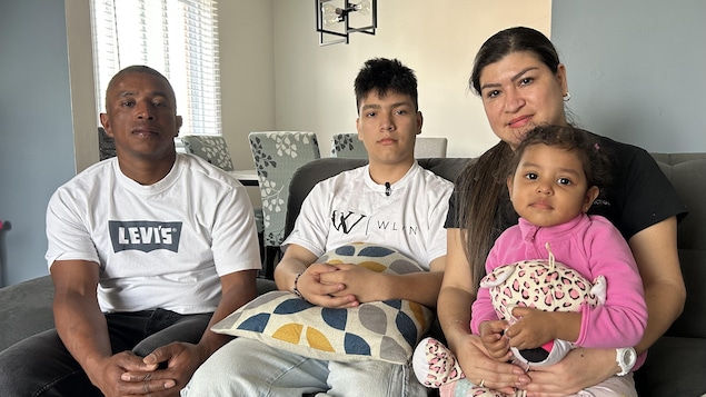 Les quatre membres de la famille sont assis sur le divan. 