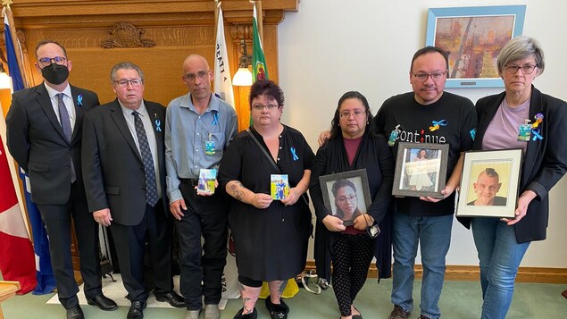 Ryan Meili, Doyle Vermette et des familles tenant des photos des personnes qui se sont suicidées.