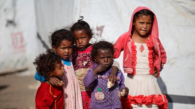 Des enfants se tiennent debout dans un camp de déplacés à Dharawan au Yémen.
