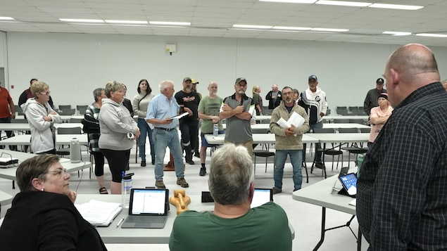 Des personnes en colère se tiennent debout devant des gens assis.