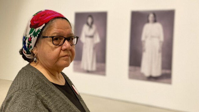 Une femme dans un musée devant deux tableaux à l'arrière-plan.