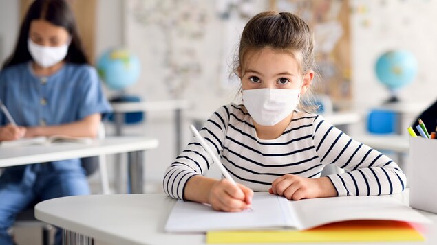 Des élèves en classe portant un masque.