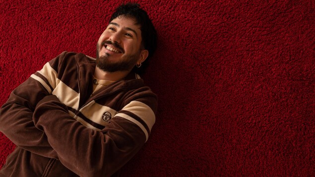 Felipe sourit, couché sur un tapis rouge