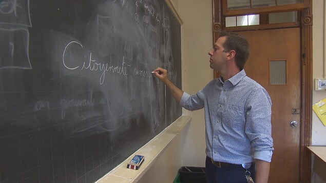 Un homme écrit sur un tableau les mots citoyenneté et numérique. Un homme écrit sur un tableau les mots citoyenneté et numérique.