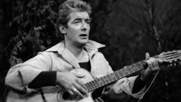 Félix Leclerc chantant sur un tabouret avec sa guitare Félix Leclerc chantant sur un tabouret avec sa guitare