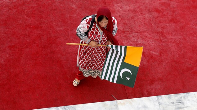 Une femme tient le drapeau du Cachemire.