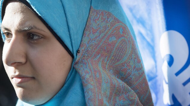 Une femme portant un hijab devant un drapeau du Québec