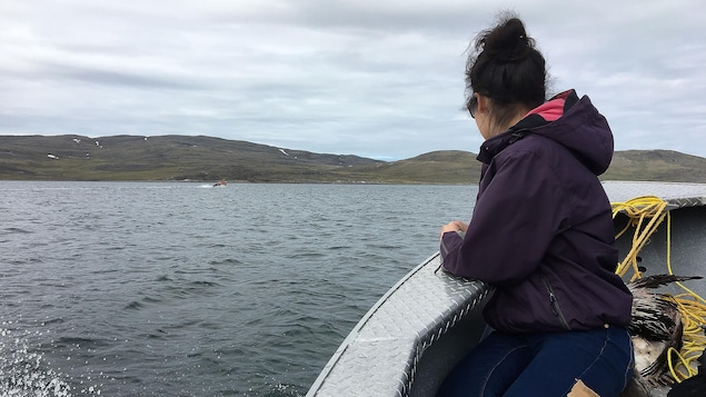 Une femme inuite sur un bateau regarde au large