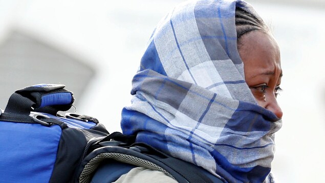 Une femme migrante, la moitié du visage couvert par un foulard, échappe une larme pendant le démantèlement du camp de la « jungle » de Calais.