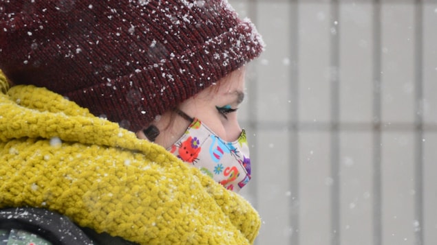 Une femme sous la neige, portant un masque.