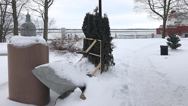 Le parc des Ursulines situé en bordure du fleuve Saint-Laurent. À l’avant-plan à gauche, une œuvre en pierre dédiée aux Ursulines. Au centre, quelques cèdres appuyés sur un support en bois artisanal.