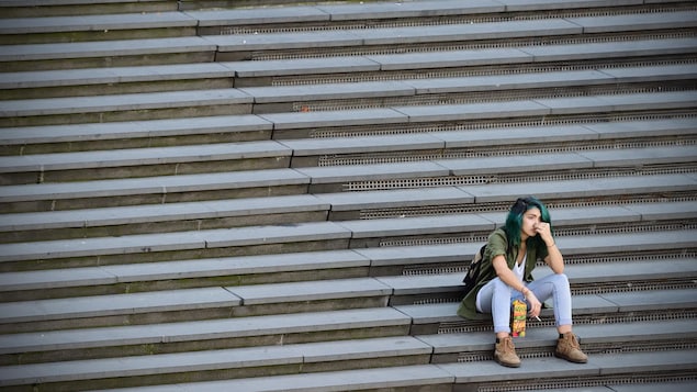 Une jeune femme est assise seule dans les marches d'un parc.