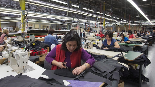 نساء على ماكينات الخياطة في مصنع في تورونتو.