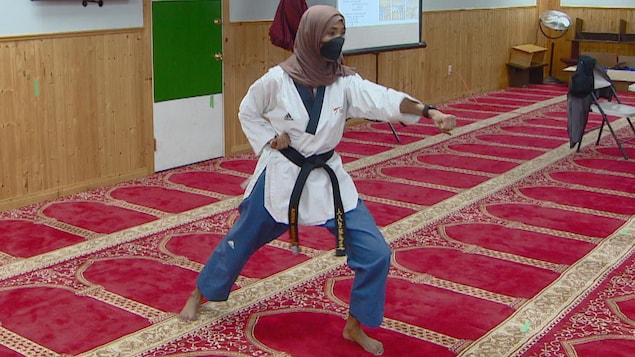 À l'intérieur d'une mosquée, une femme musulmane montre à d'autres femmes comment se défendre physiquement lors d'une agression.